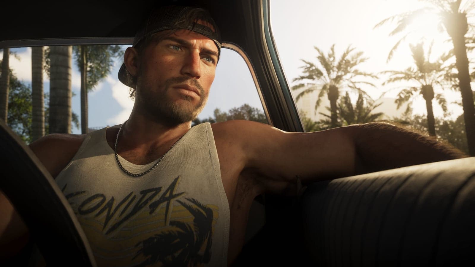 Jason in a backwards cap and a Leonida tank top sits in the back of an old car