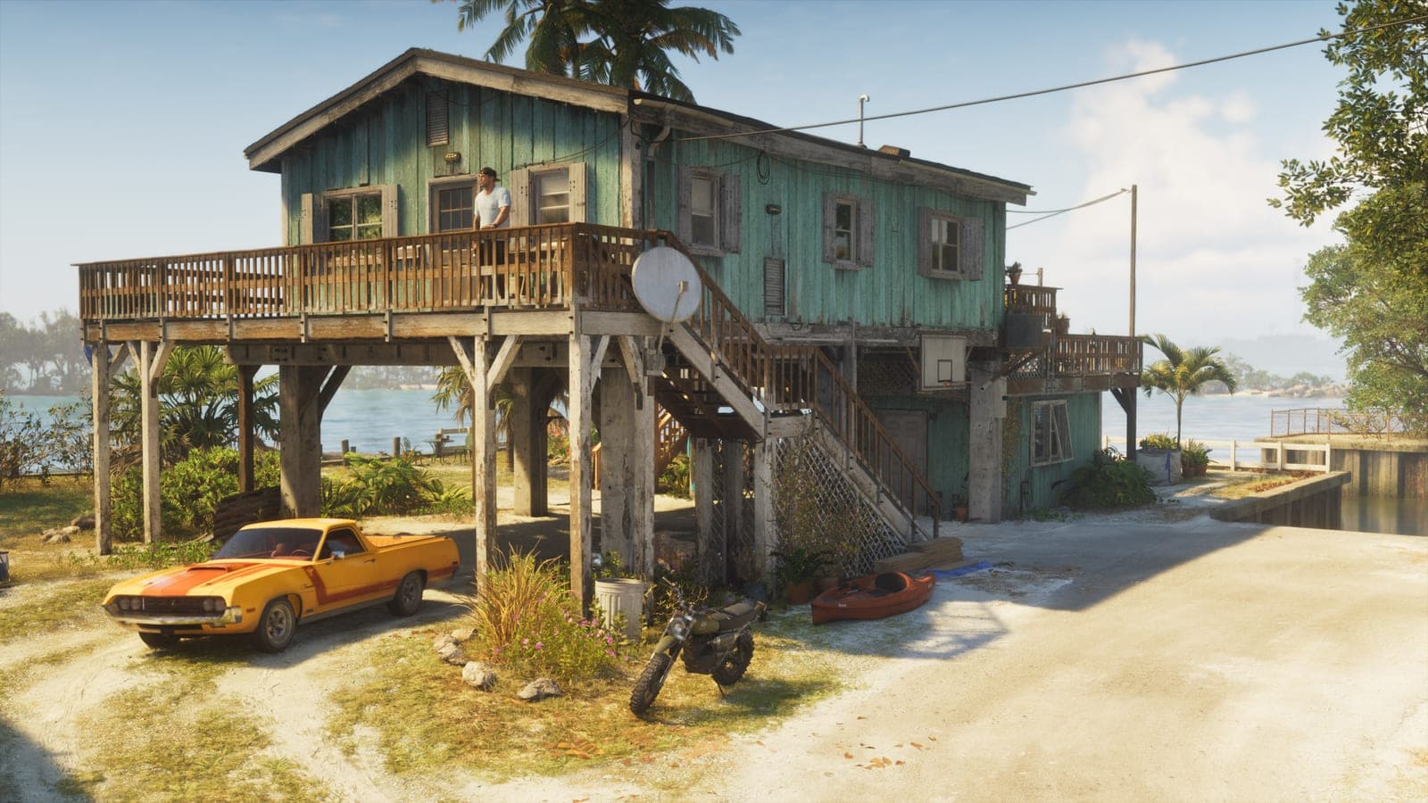 A wooden stilt house by the water with a pickup, a motorcycle and a kayak outside