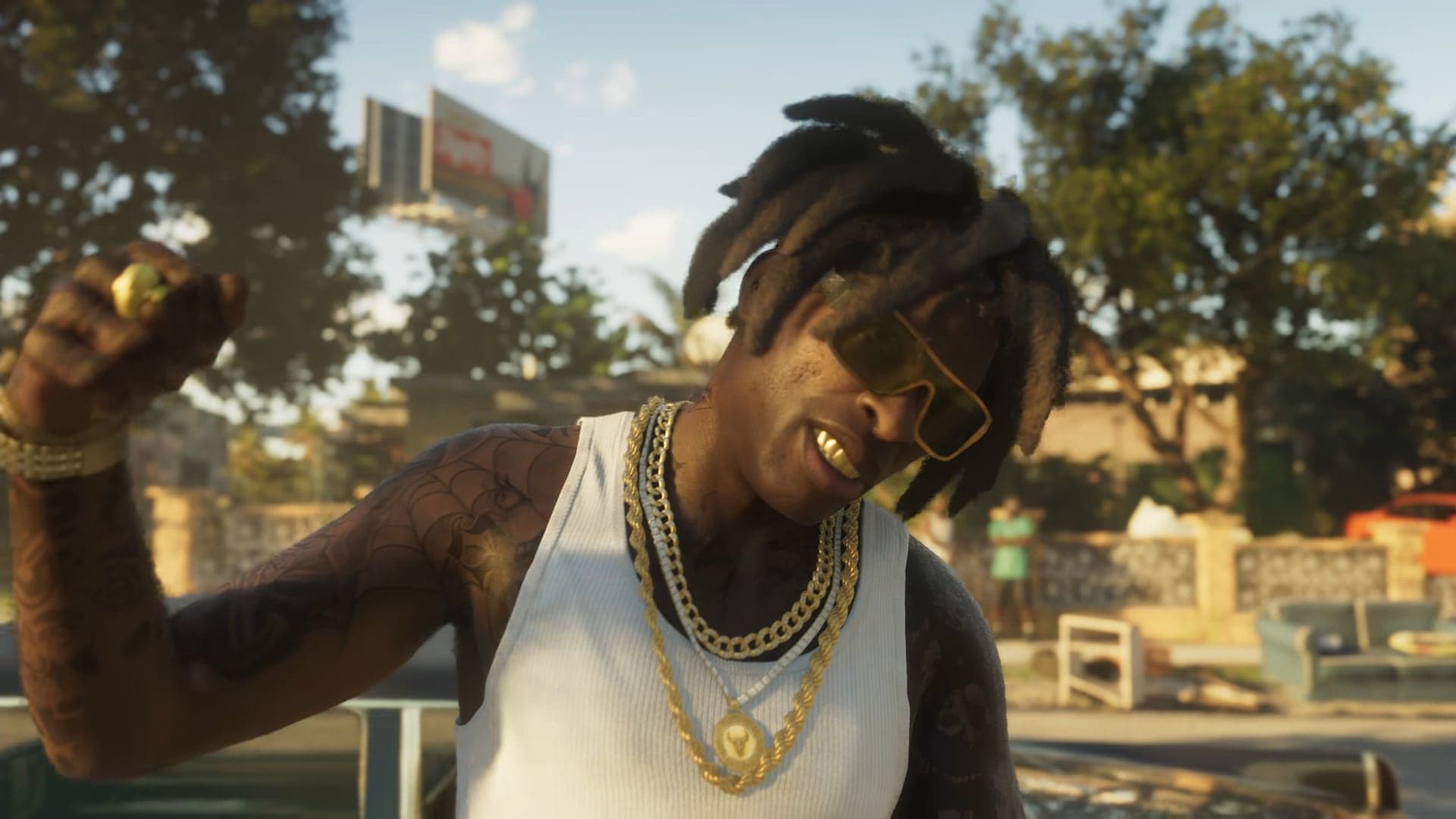 A man in gold chains, a white tank top and yellow sunglasses raising his hand on a sunny street