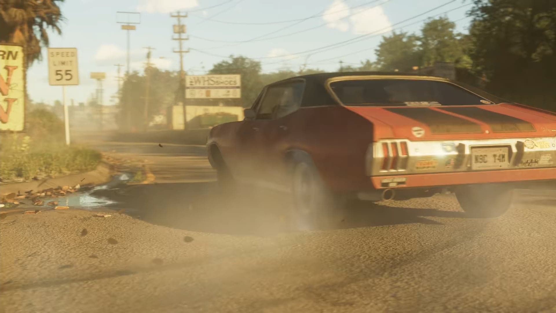 A red car skidding on a dirt road in a cloud of dust