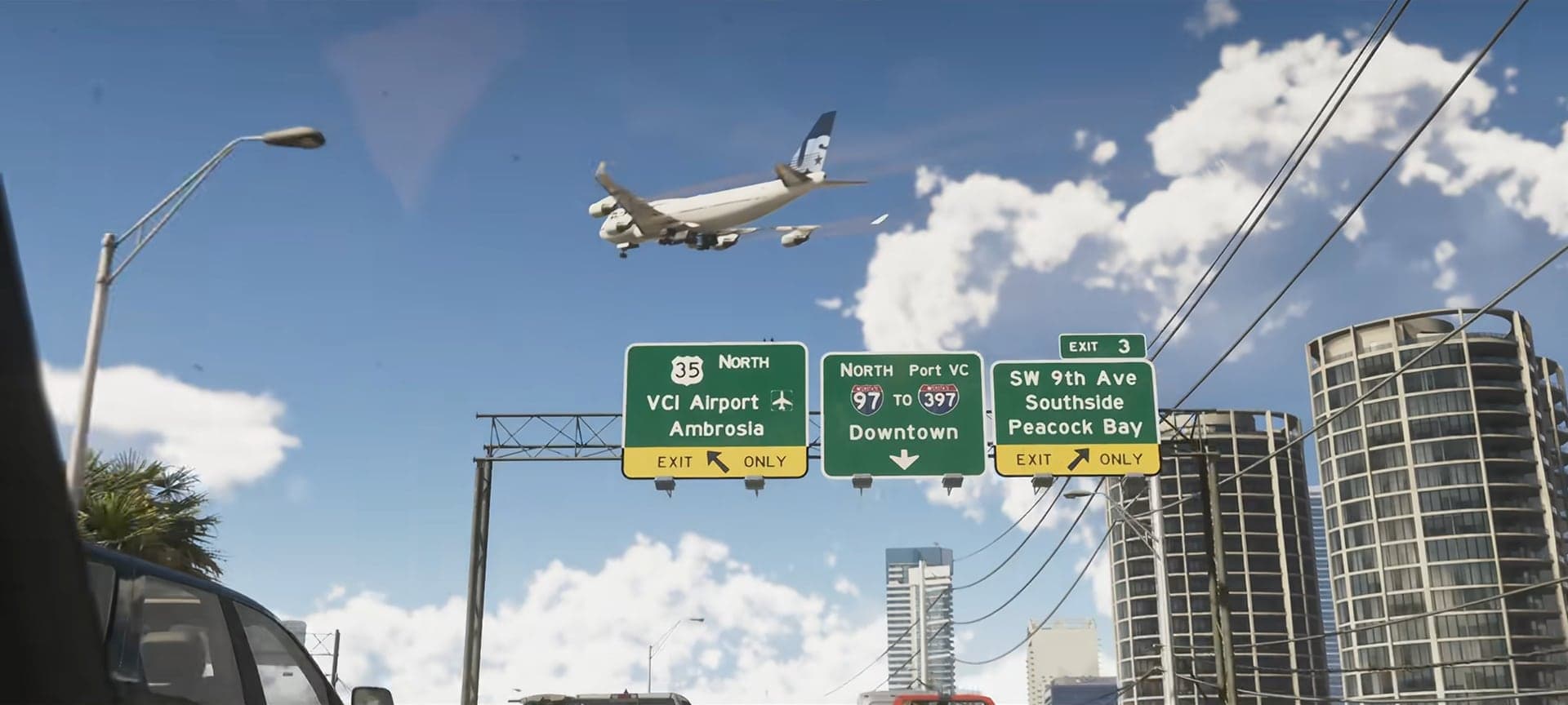 A plane over a highway with green signs for VCI Airport, round towers on the right