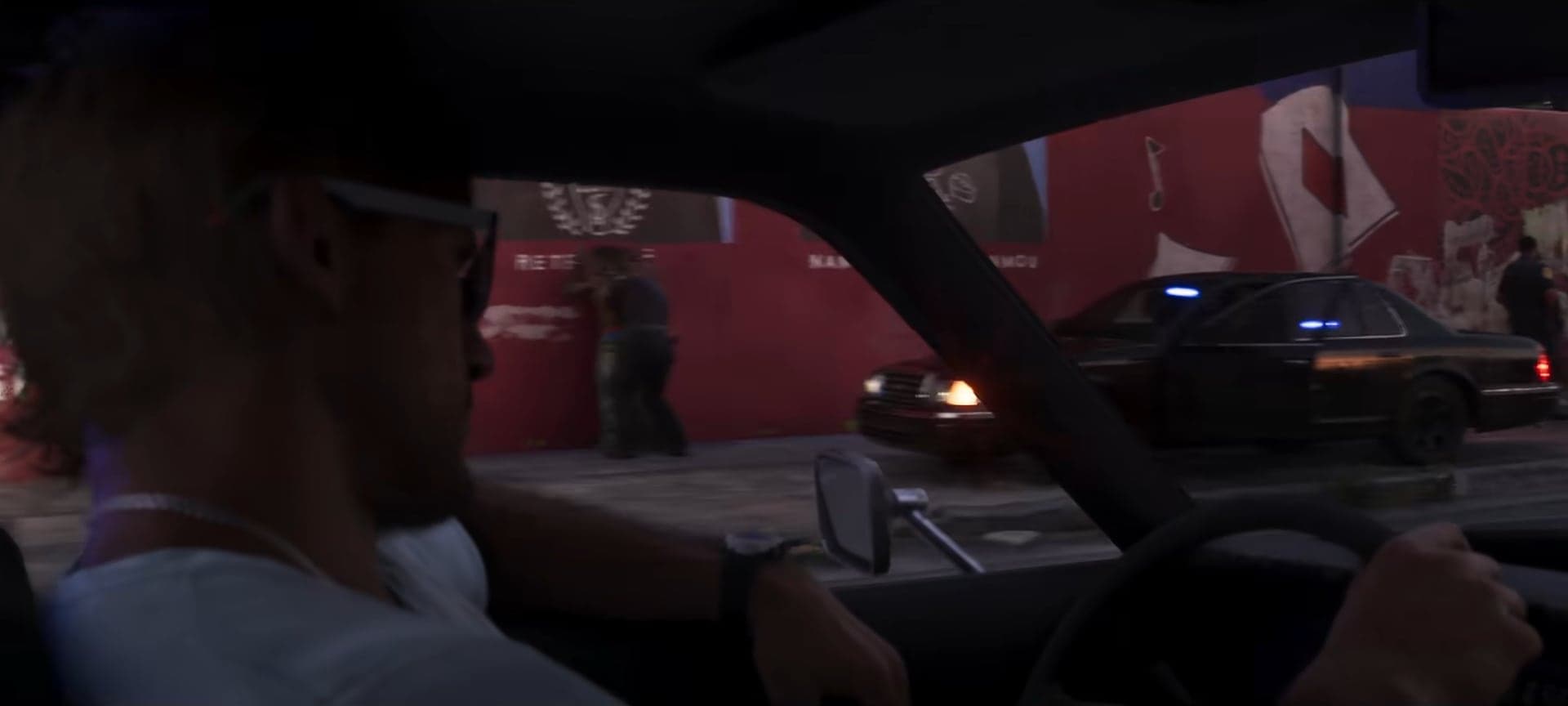 A view from a car: a police cruiser by a wall with murals