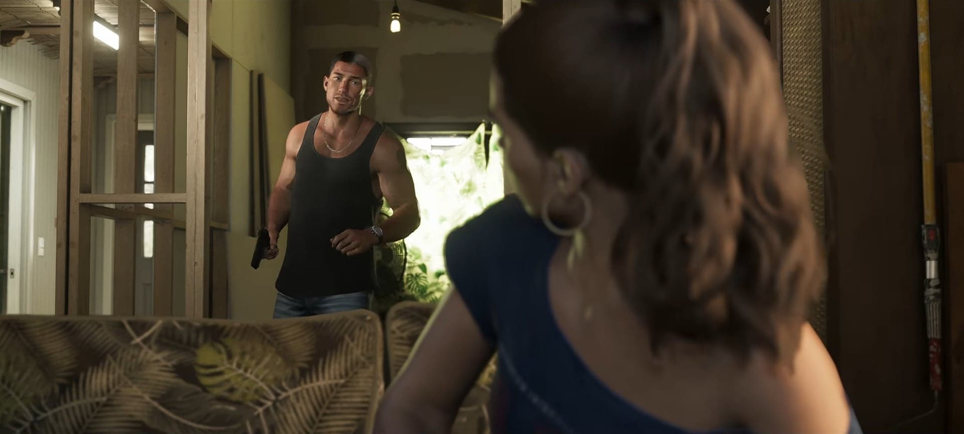 Jason in a tank top walking into a living room as Lucia turns around on the couch
