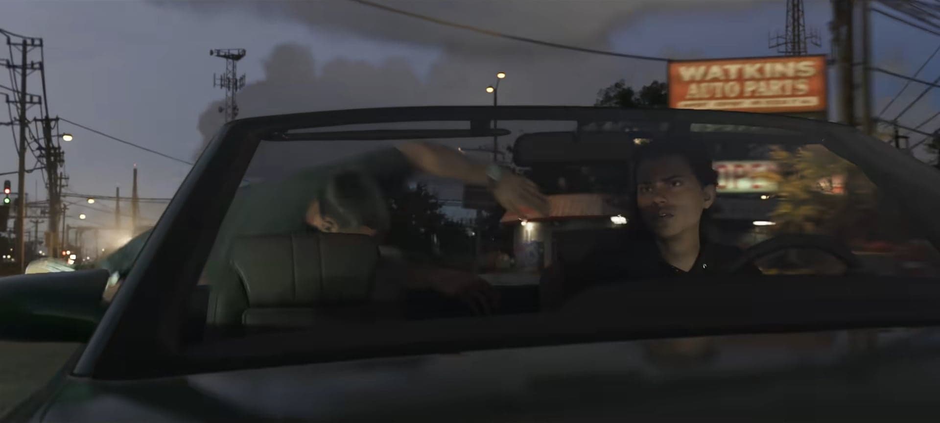 Two people in a convertible at night by the Watkins Auto Parts sign
