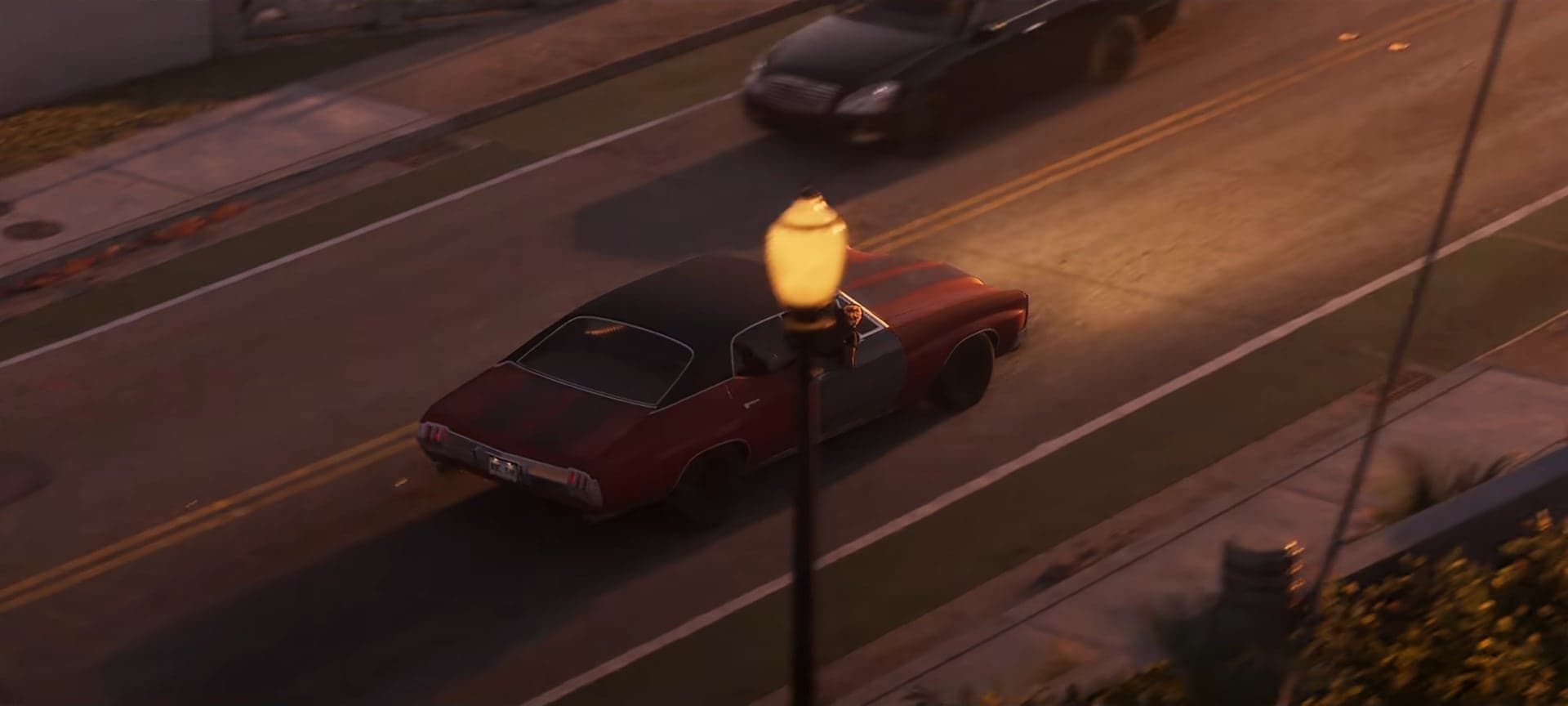 A red muscle car on an evening street, seen from above