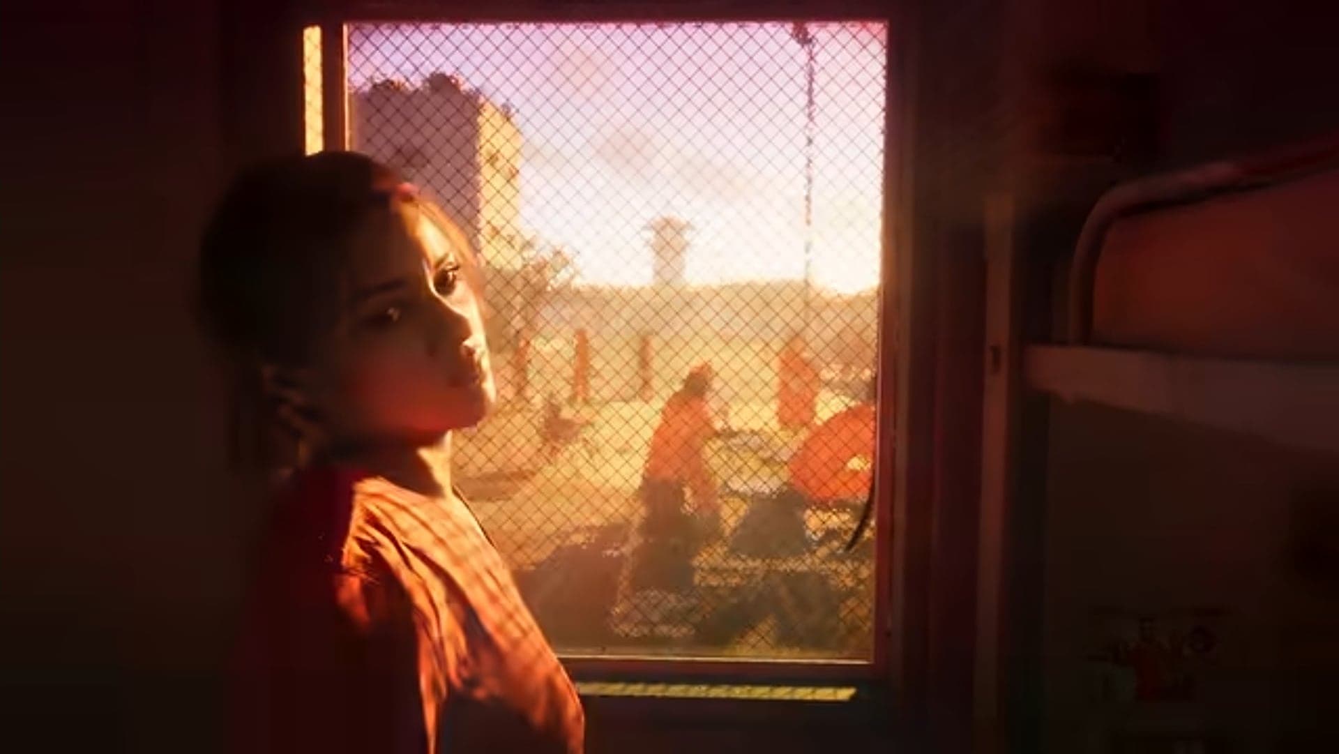 Lucia at a barred window, with a prison yard and people in orange jumpsuits behind her
